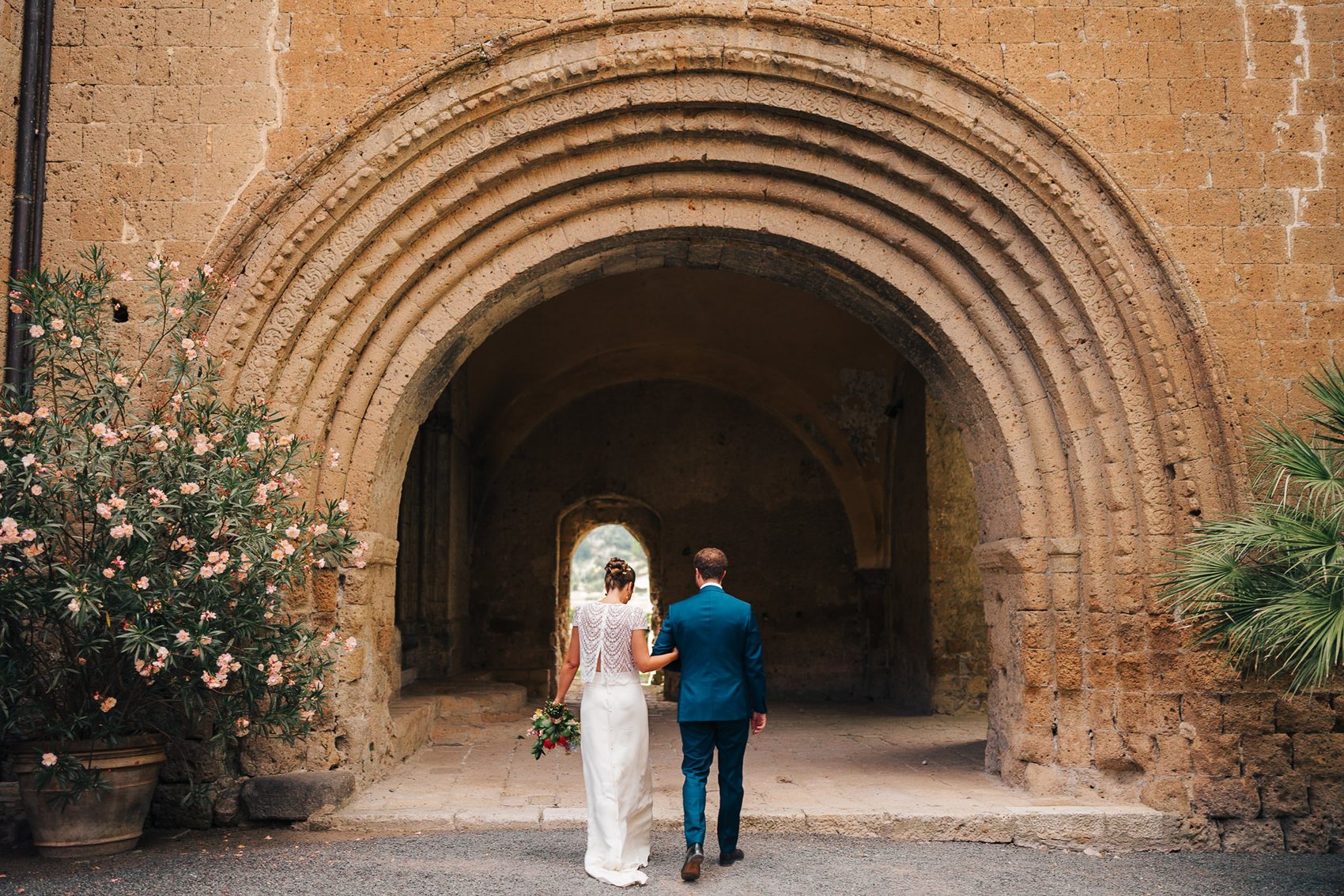 Couple walking through a grand arched Italian doorway